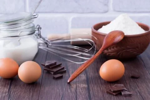 Products and objects for baking chocolate cake on dark wooden table. Concept Stock Photos