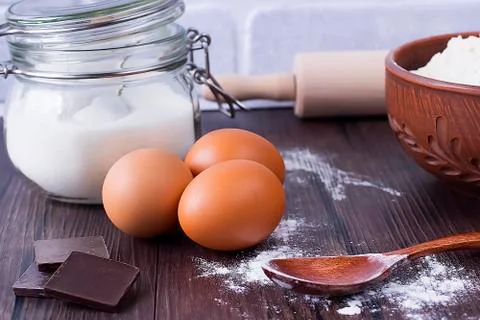 Products and objects for baking chocolate cake on dark wooden table. Concept Stock Photos