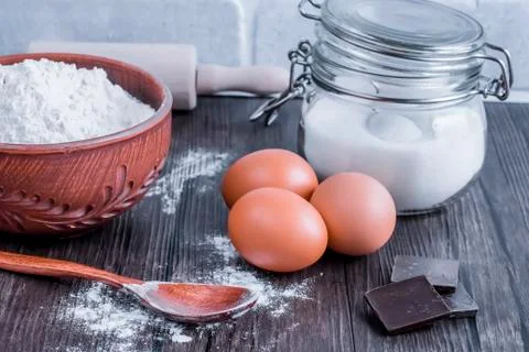 Products and objects for baking chocolate cake on dark wooden table. Concept Stock Photos