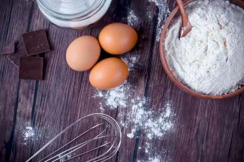 Products and objects for baking chocolate cake on dark wooden table. Concept Stockfoto's