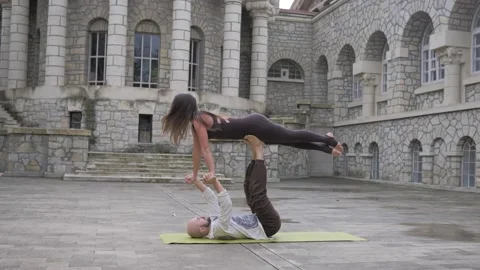 Professional acrobatic yoga. couple practising acro exercises on mat outdoors Stock Footage 150660714