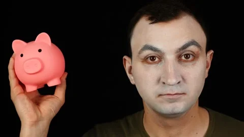 Professional actor with white makeup on face holding piggy bank in his hands. Stock Footage 150742643