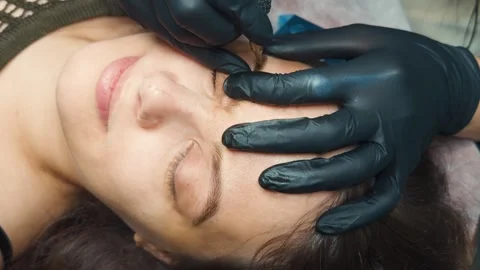 Professional aesthetician performing microblading procedure on a client's Stock Footage 331574057