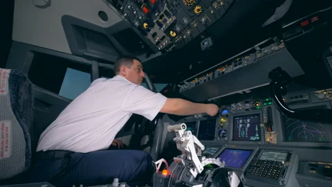 Professional aiplane pilot is turning indicators on a cockpit cabin flight deck. Stock Footage 93655541