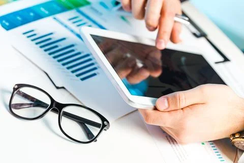 Professional analyzing data on tablet while reviewing charts and graphs in Stock Photos