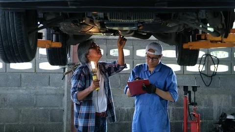 Professional and young mechanic checking car suspension at garage. Stock Footage 122266800