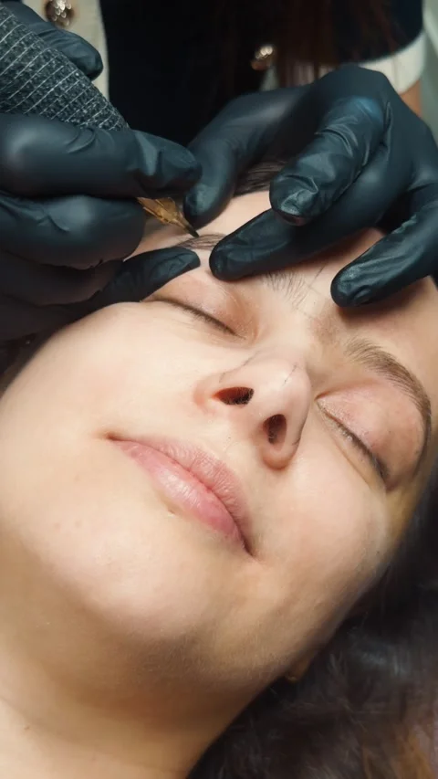 Professional artist performing microblading procedure on woman's eyebrows, Stock Footage 331574859