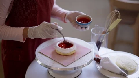 Professional Asian baker spreading red fruit topping on white frosted cake .. Video stock 345102743
