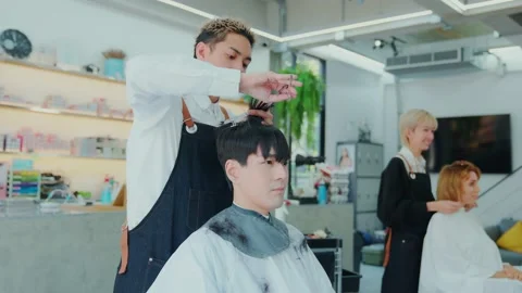 Professional Asian barber uses scissors and a comb to trim hair for customers Stock Footage 153882883