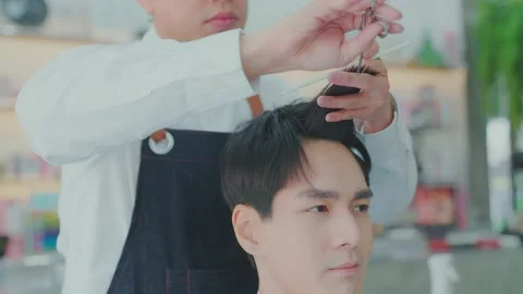 Professional Asian barber uses scissors and a comb to trim hair for customers Stock Footage 153969633