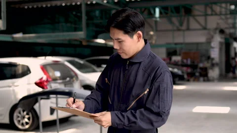 Professional Asian mechanic standing in front of garage inspecting car repa.. Stock Footage 243732192