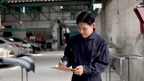 Professional Asian mechanic standing in front of garage inspecting car repa.. Vídeo Stock 243732363