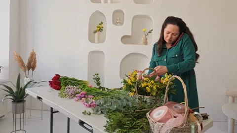 A professional assembles flower arrangement with mimosa and tulip. Stock Footage 237623569