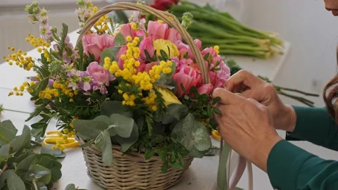 A professional assembles flower arrangement with mimosa and tulip. Stock Footage 237623826