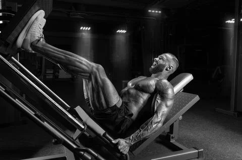 Professional athlete performs a leg exercise. Bodybuilding, fitness, sports.. Stock Photos