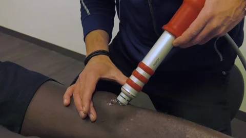 Professional Athlete Runner Gets Shockwave Treatment From Coach On His Knee Stock Footage 130676712