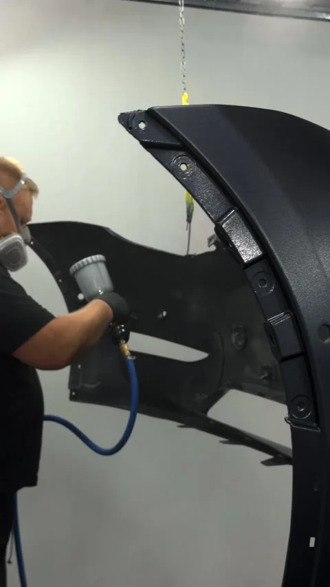 Professional auto body painter applying finish to car bumper with spray gun Stock Footage 341134715