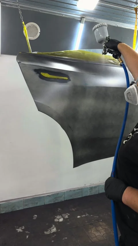 Professional auto body painter applying primer to a car panel in a spray booth Stock Footage 341134776