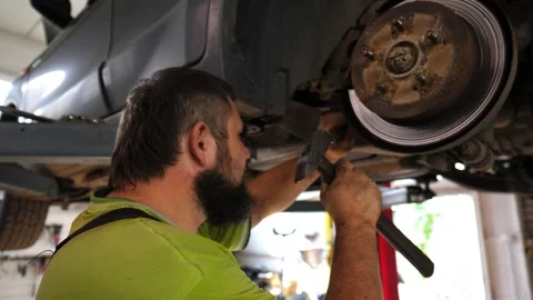 Professional auto mechanic in uniform repairs detail of car using hammer Stock Footage 307384468