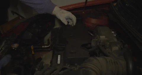 A professional auto mechanic wearing protective gloves unscrews the engine cover Stock Footage 317241159