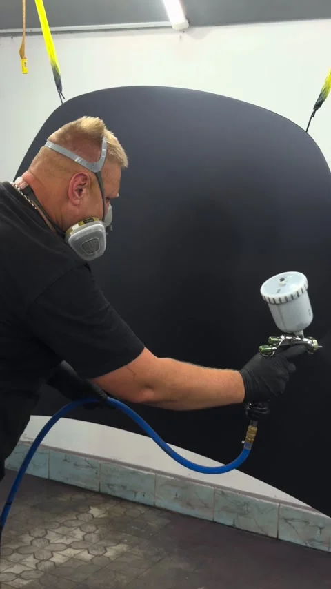 Professional auto painter applying matte black finish with spray gun Stock Footage 341134695