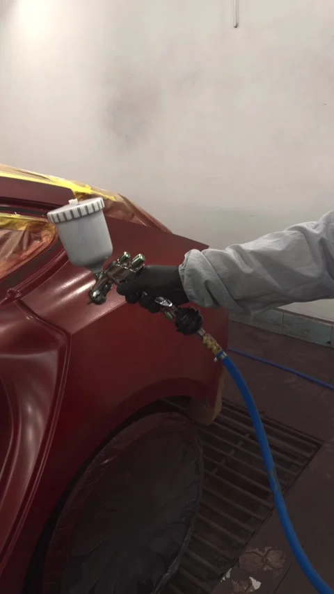 Professional auto painter applying red paint with spray gun in a booth Stock Footage 339326940