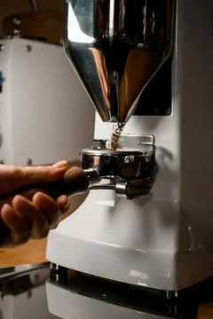 Professional automatic coffee grinder pours ground coffee into portafilter in Stock Photos