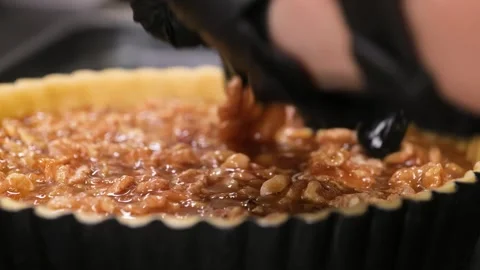 Professional Baker Hand in Black Glove Pressing Walnuts into Caramel Tart in Flu Stock Footage 337751451