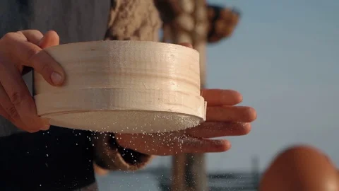 Professional baker hands sift flour through a wooden sieve on the table sun Video stock 129777536
