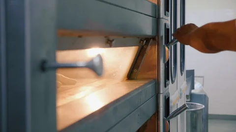 Professional baker puts raw bread into the oven in a commercial kitchen Stock Footage 91297732