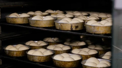 A professional baker putting a tray full of buns into the oven for baking. Stock Footage 108098601