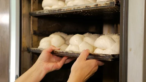 A professional baker putting a tray full of bread in a large industrial oven. Stock Footage 109473104