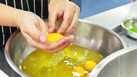 Professional baker separating egg yolk from white by hand over a bowl. Stock-Footage 346606333