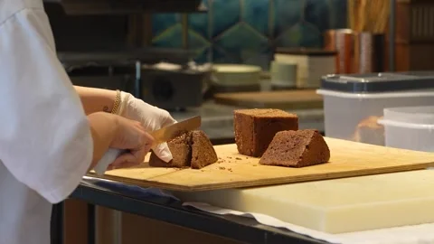 Professional Baker Slicing Dark Rye Bread with Seeds. Chef slicing a triang.. Video stock 331213592