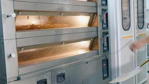 Professional baker taking bread out from the oven in a commercial kitchen Stock Footage 91317568