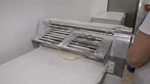 Professional baker using dough sheeter machine in a bakery kitchen Stock Footage 331248230
