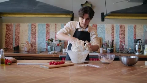 Professional baker working in bakery shop, kneading dough for bread, using Stock Footage 261437646