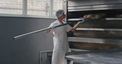 Professional bakery workers unloaded the cooked bread from oven and load to the Stock Footage 112143305