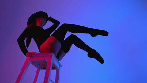 Professional ballet dancer in hat sitting on high chair on multi-colored Stock Footage 154971651