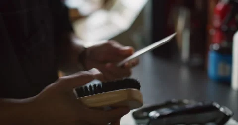 Professional barber cleaning comb with a brush in interior hipster barbershop wi Video stock 199458858