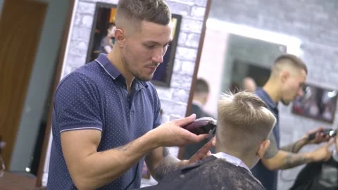 Professional barber cuts a boy 動画素材 149860346