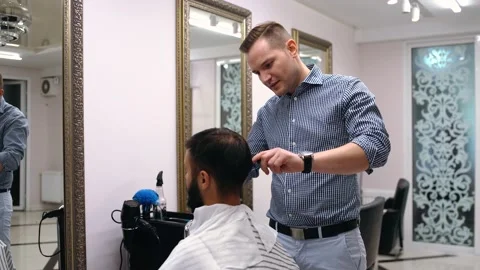 The professional barber discusses with the client how the cutter should be Stock Footage 136458406