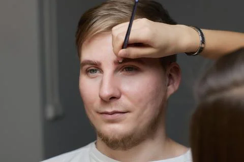 Professional barber doing threading procedure and correcting shape of eyebrows Stock Photos