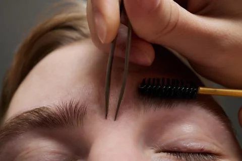 Professional barber doing threading procedure and correcting shape of eyebrows Stock Photos