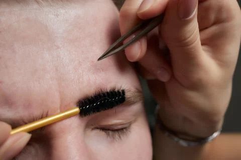Professional barber doing threading procedure and correcting shape of eyebrows Stock Photos