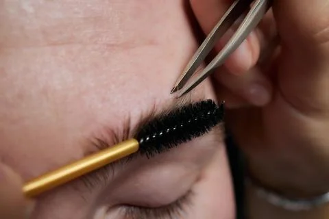 Professional barber doing threading procedure and correcting shape of eyebrows Stock Photos