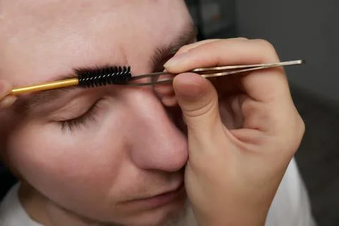 Professional barber doing threading procedure and correcting shape of eyebrows Stock Photos