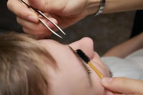 Professional barber doing threading procedure and correcting shape of eyebrows Stock Photos