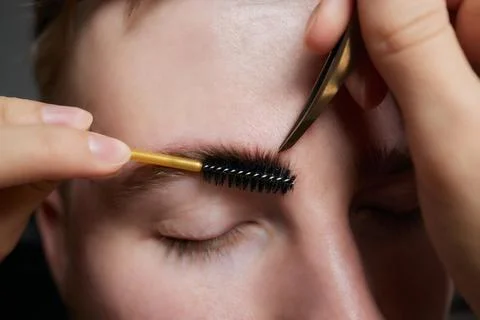 Professional barber doing threading procedure and correcting shape of eyebrows Stock Photos