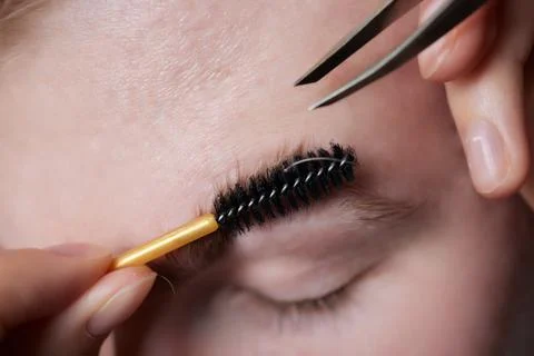 Professional barber doing threading procedure and correcting shape of eyebrows Stock Photos